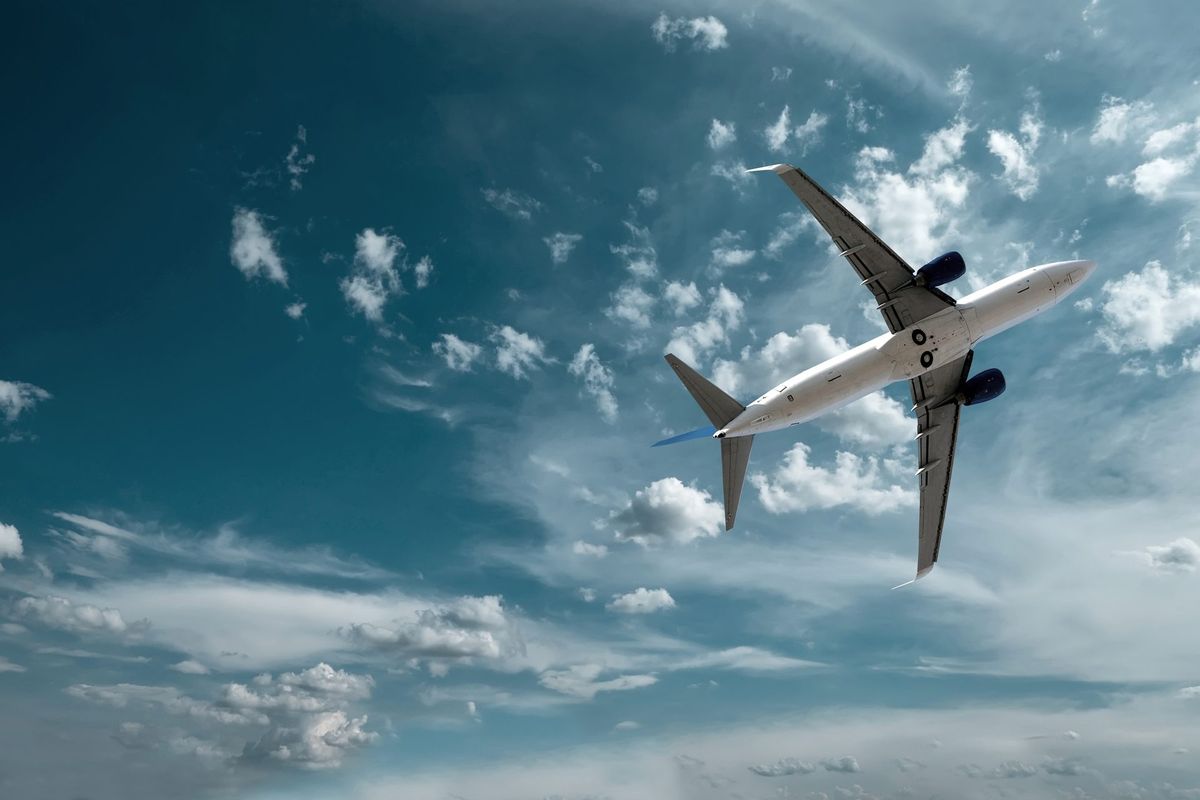 Commercial aircraft viewed from below against a dramatic sky